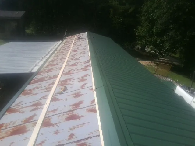 Old rusted panels beside newly installed green metal roofing — Wind Damage Roof Repair by Roofing Brothers in Mount Rainier
