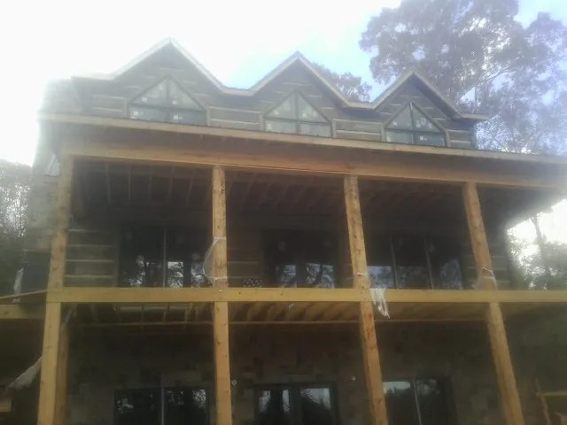 Dormers and porch framing on a large log home under construction — Roof Coating work by our crew in Mount Rainier