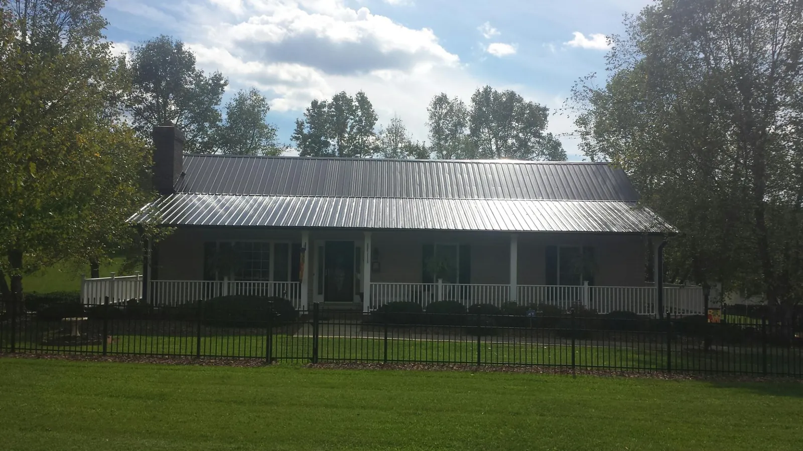 Gray metal roof on a brick ranch with a full width front porch — Gutter Guard Installation work by our crew in Mount Rainier