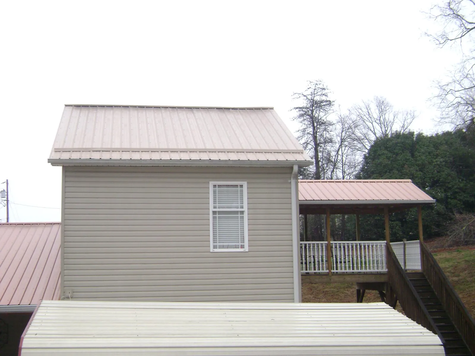 Tan metal roofs on a two story addition and attached porch, from a Roof Replacement job in Mount Rainier