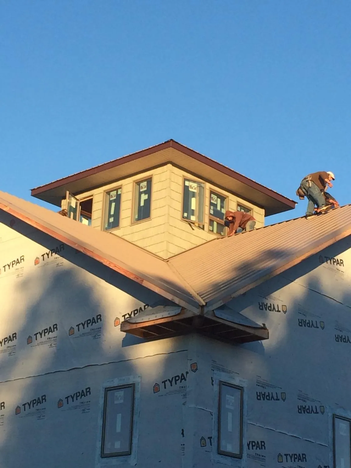 Roofers working around a rooftop cupola on a new metal roof at sunset — Roof Waterproofing in Mount Rainier by Roofing Brothers